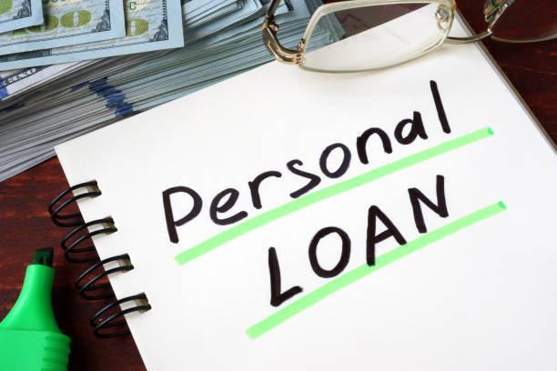 personal loan written on a notebook and dollars.